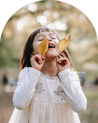 A little girl proudly displays a vibrant green leaf.