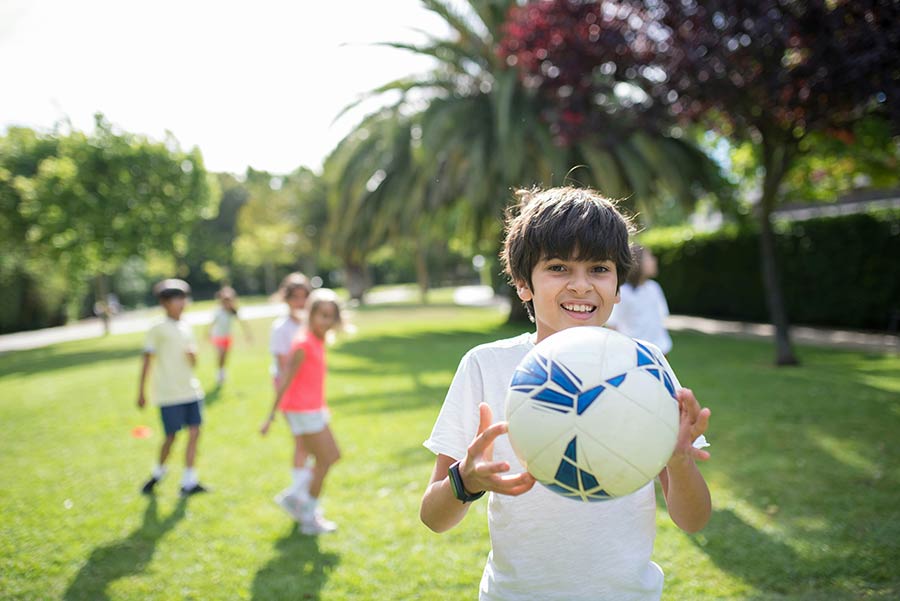 happy boy playing soccer with friends