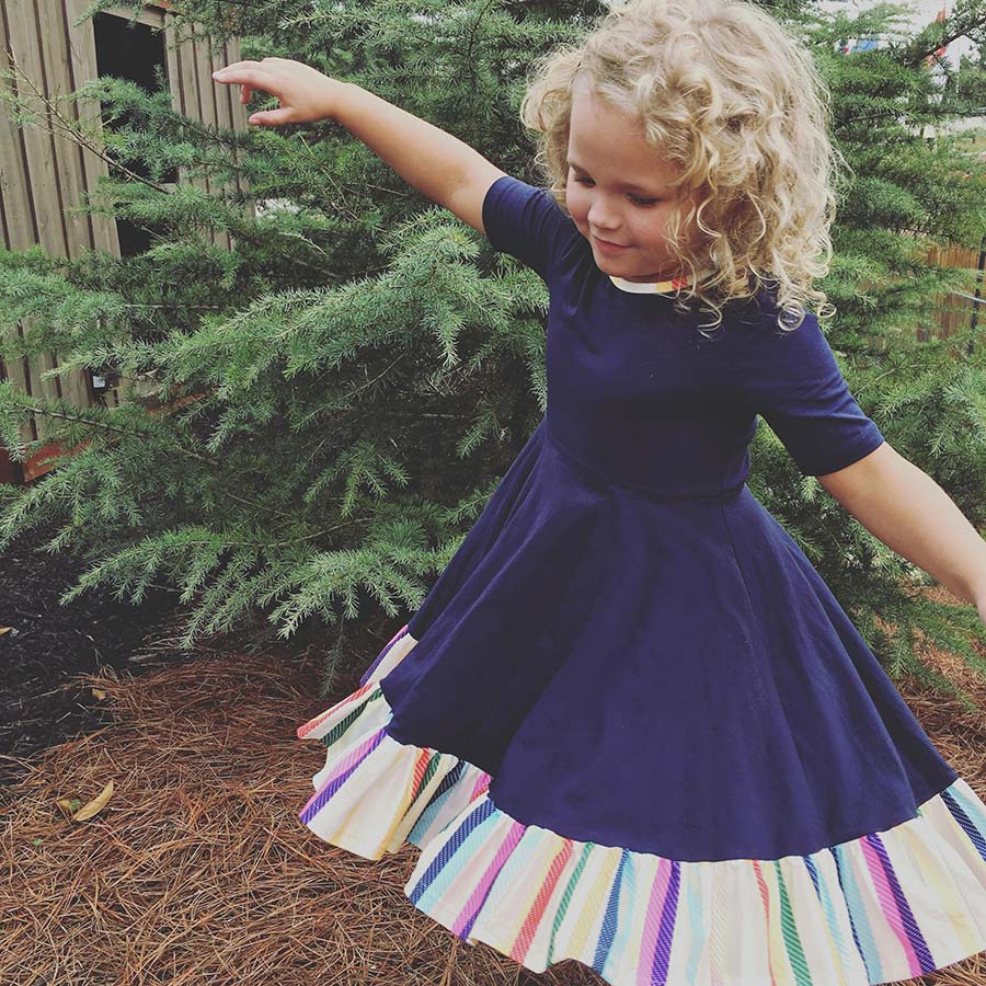 Happy little girl in a dress pretending to fly