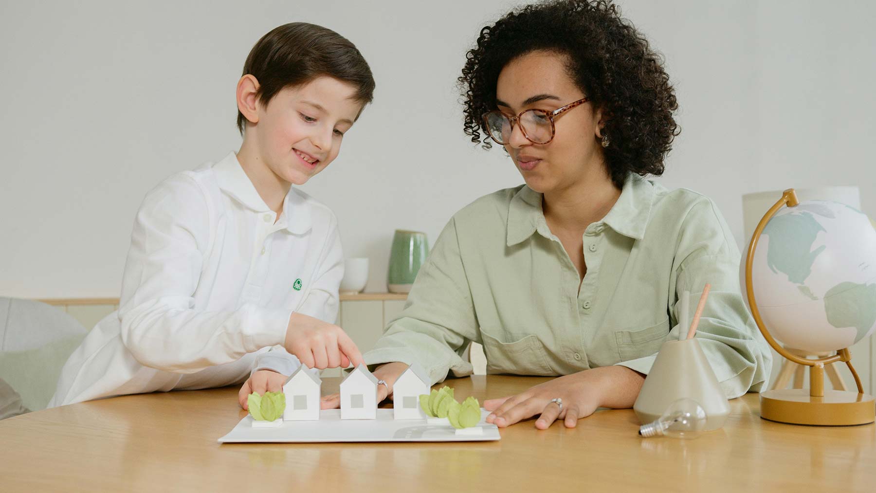 Young boy and therapist playing with small paper houses