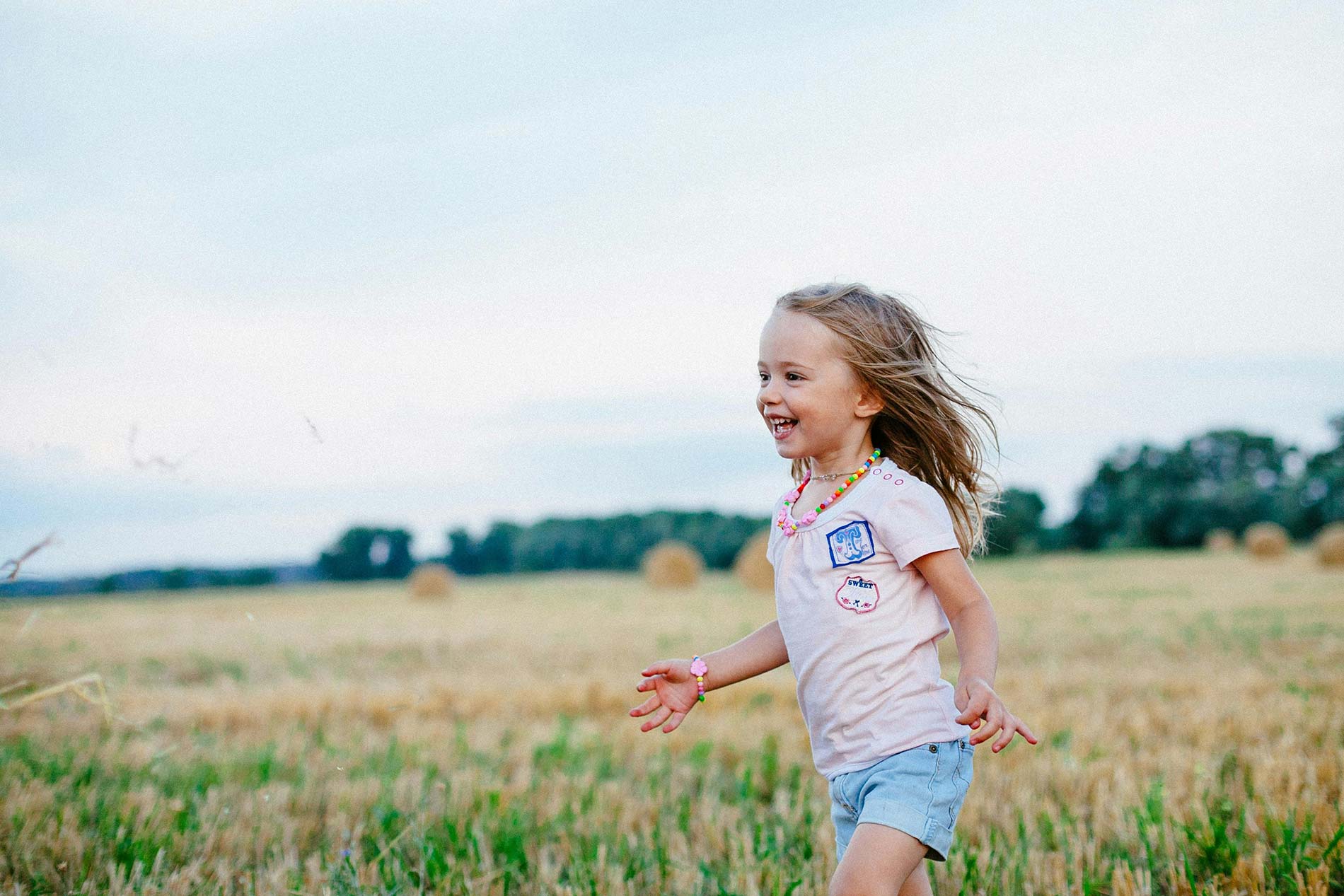 A laughing little girl running through a field